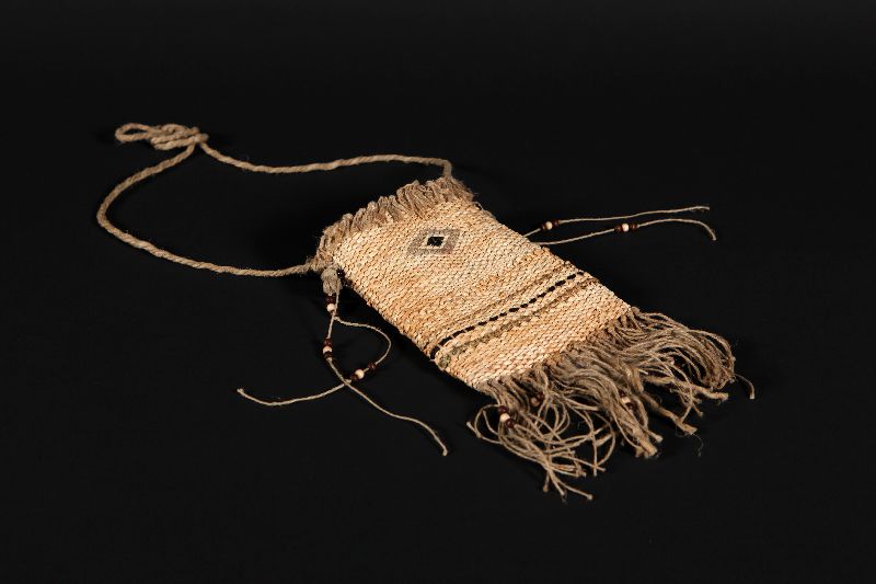 A bag made of woven corn husks, decorated with a diamond shape motif.