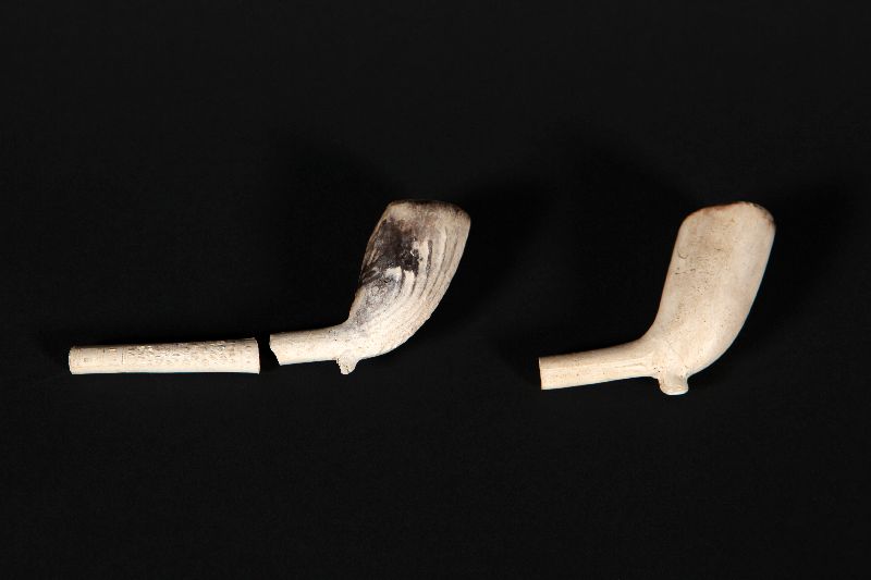 Deux reproductions de pipes en plâtre cassées, celle de droite est incomplète.