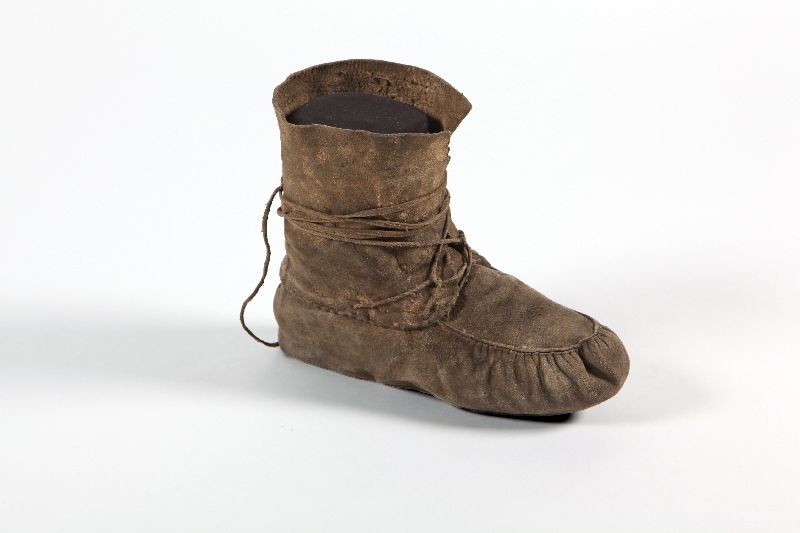 A leather moccasin. The laces are wrapped around the ankle.